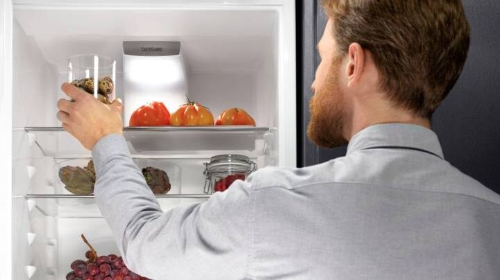 A man opening a refrigerator 